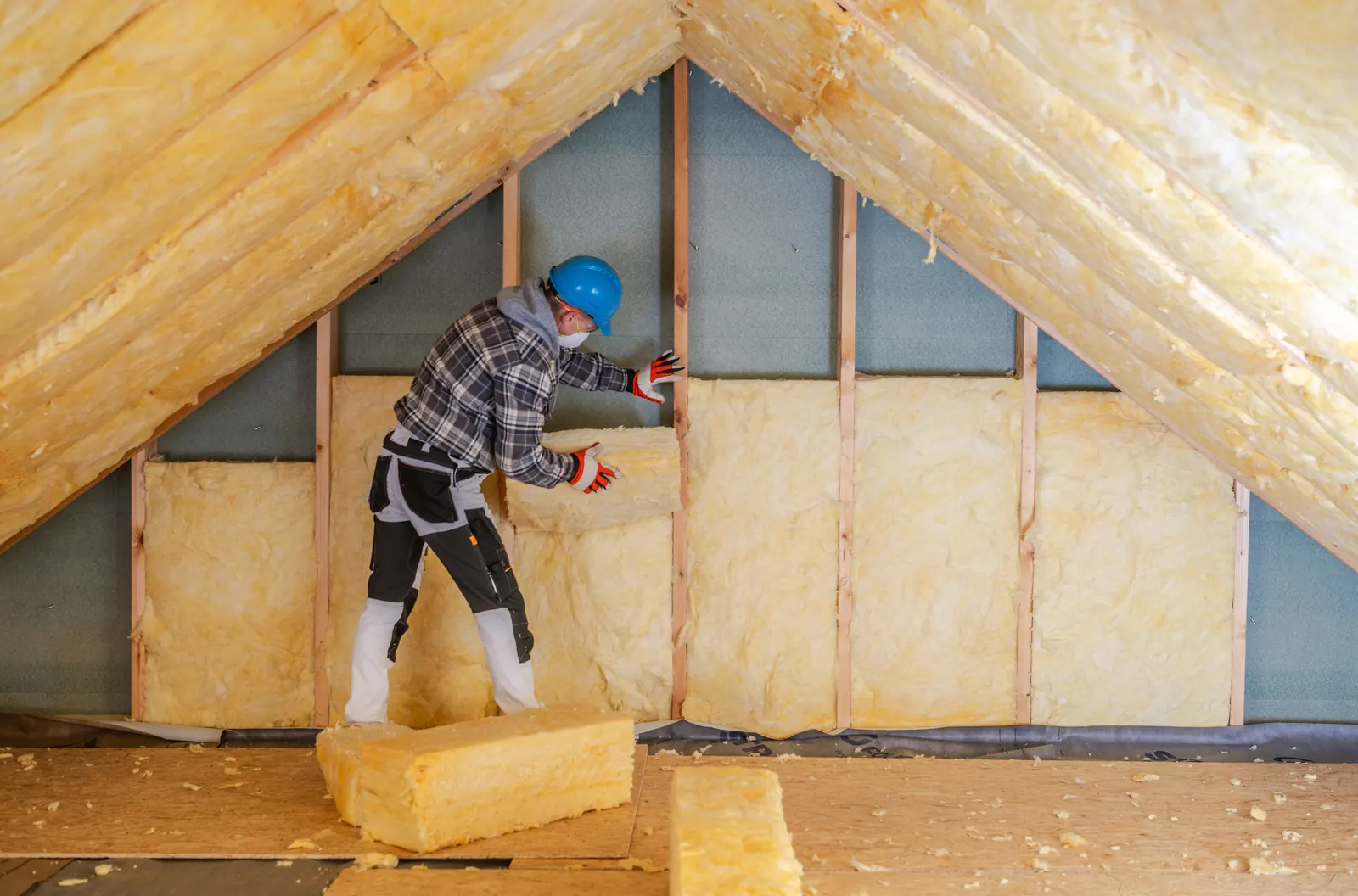 Worker installing insulation in a home attic