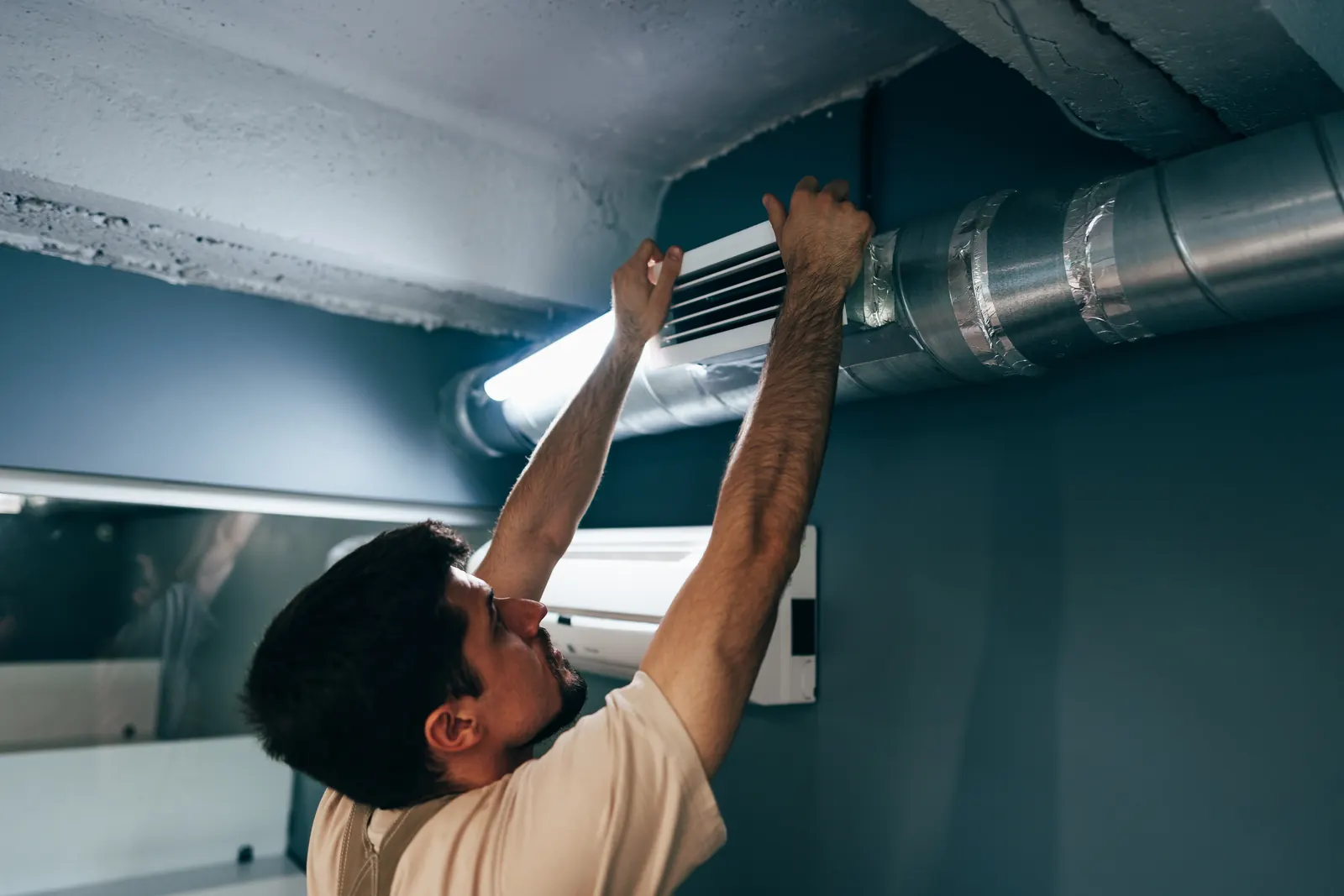 Technician working on ductwork along a home's ceiling